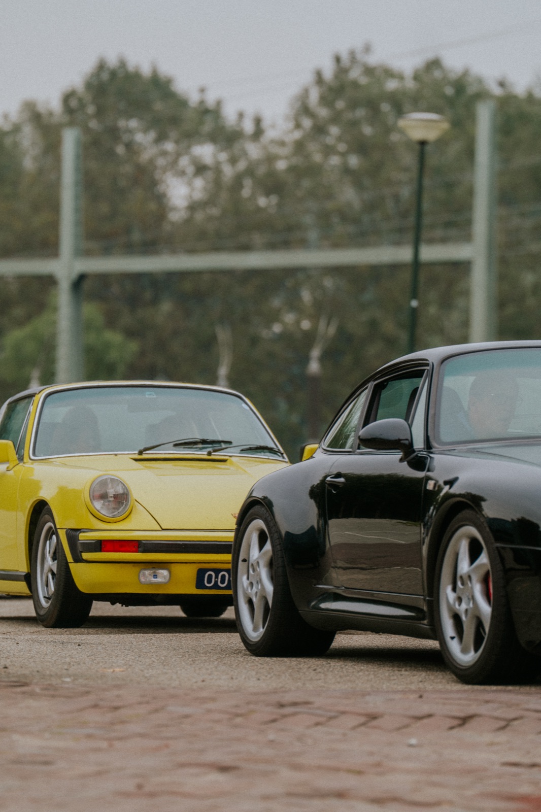 Twee klassieke Porsches op kinderkopjes tijdens de rally